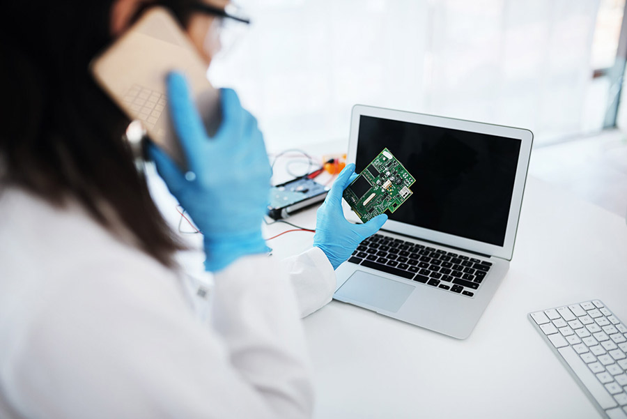 Digital forensics specialist examining a circuit board while consulting on a data recovery case